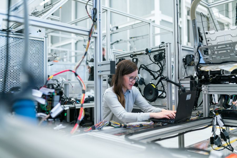 Engineer reviewing a design at a workstation with a laptop and electronics